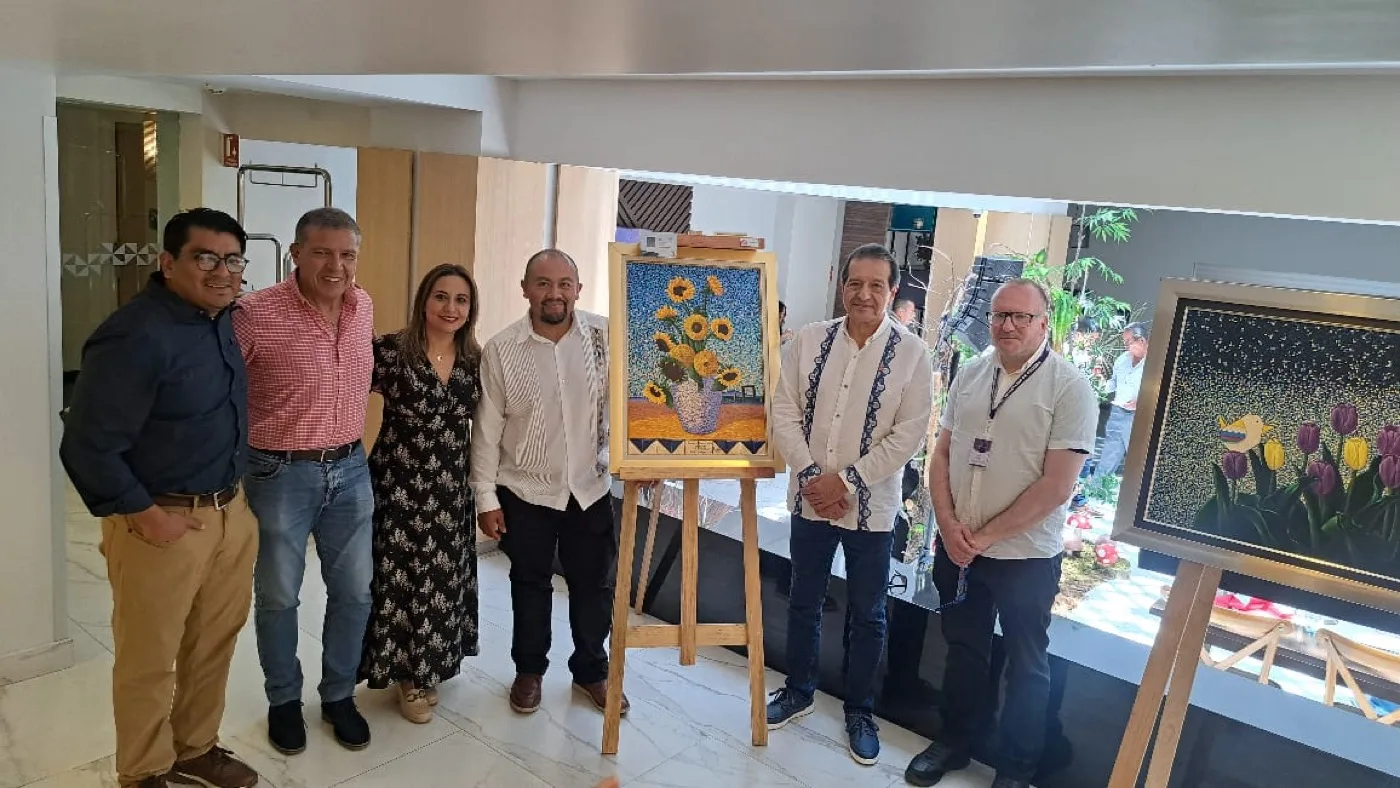 Alejandro Muñoz Romero with guests beside a painting on an easel